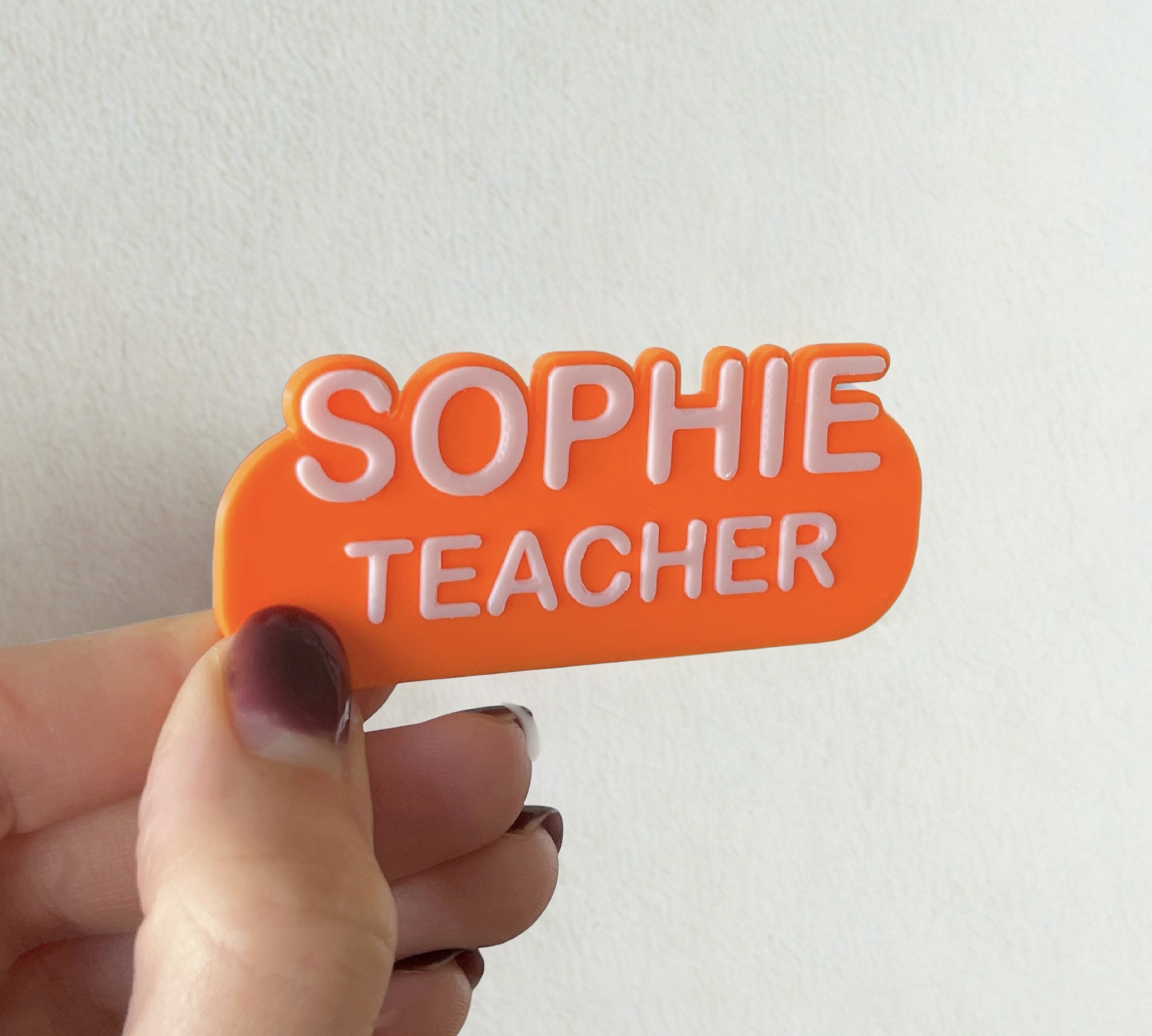 Vibrant orange Kind Badge for Sophie Teacher held in hand showing size and quality